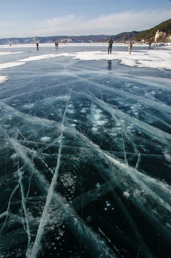 Cracked lake Baikal in winter, people walking it in the distance royalty free stock photo