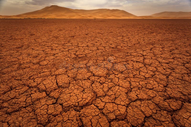 Cracked pattern of dry lake bed and sand dunes stock photography