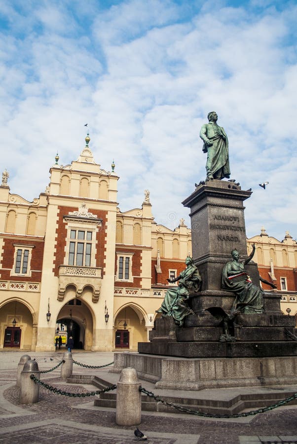 Cracovie - statue d'Adam Mickiewicz et de Sukiennice buidning avec hôtel de ville à l'arrière-plan photo libre de droits Cracovie - statue d'Adam Mickiewicz et de Sukiennice buidning avec hôtel de ville à l'arrière-plan photo libre de droits