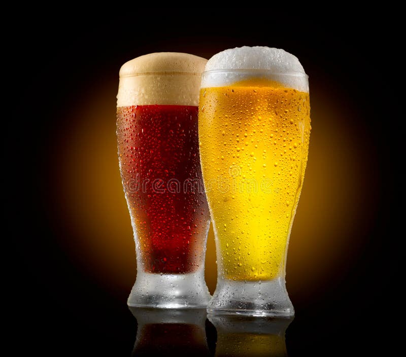 Craft beer. Two glasses of cold light and dark beer isolated on black stock images