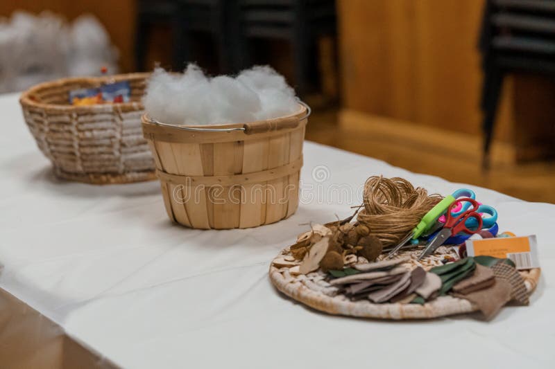 Craft Supplies Table Setting for DIY Project: Baskets, Cotton, Scissors and Fabrics on White Cloth royalty free stock photos