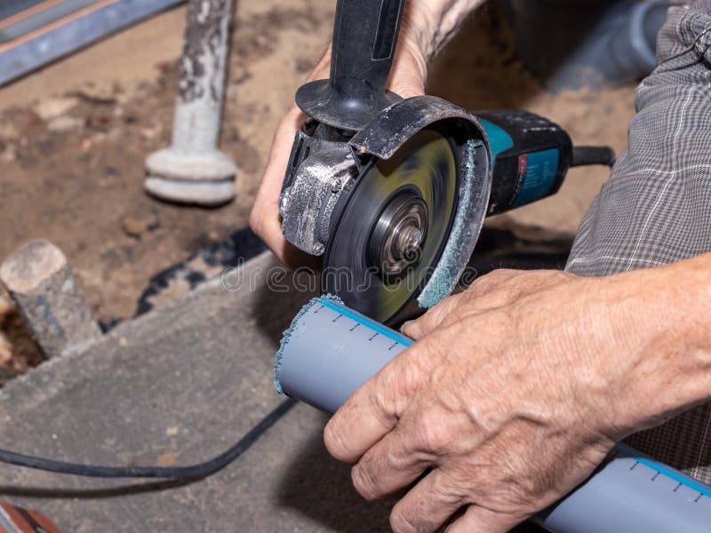 A Craftsman Cuts a PVC Pipe Using an Xangle Grinder Stock Photo
