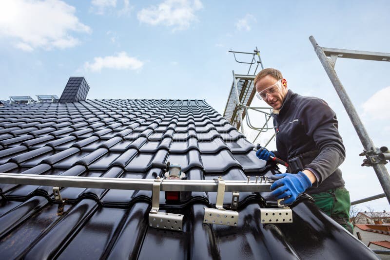 craftsman-installing-the-solar-panel-mounting-system-on-a-roof-stock