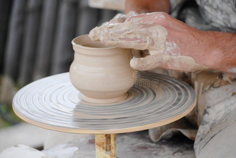 Craftsman making vase from fresh wet clay on pottery wheel