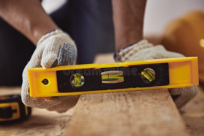 Male carver checking level of wooden plank in his shop. Construction concept. Male carver checking level of wooden plank in his shop. Construction concept.