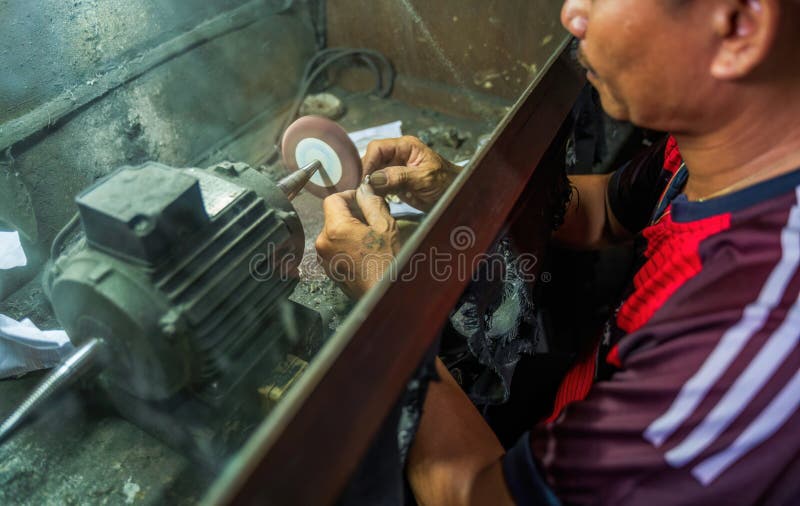 A craftsman skillfully uses a polishing machine to refine a small object stock images