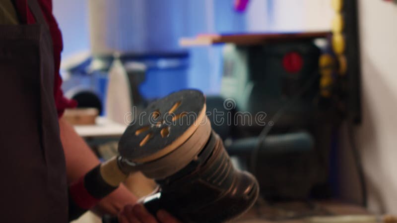 Craftsperson putting sandpaper discs on sander device