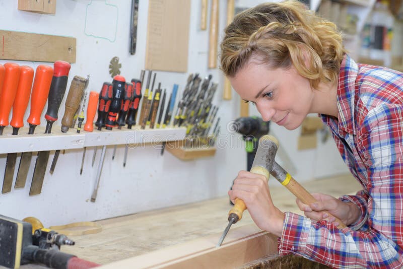 Craftswoman working with chisel and hammer in workshop stock images Craftswoman working with chisel and hammer in workshop stock images