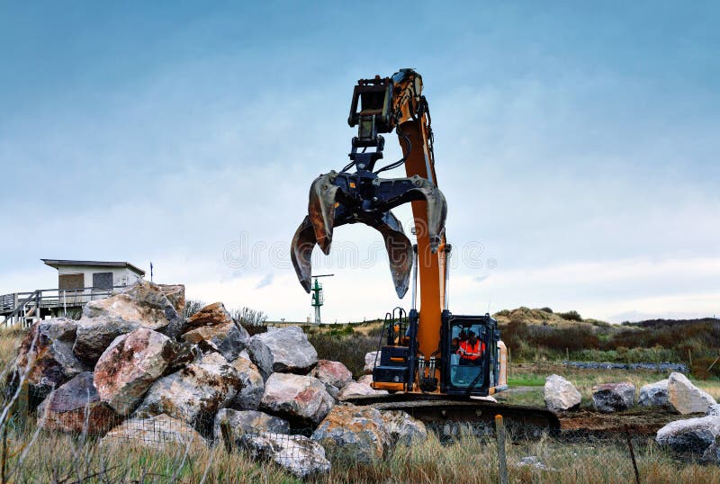 Crane or Excavator Equipped with a Grapple Handling Large Rocks Stock