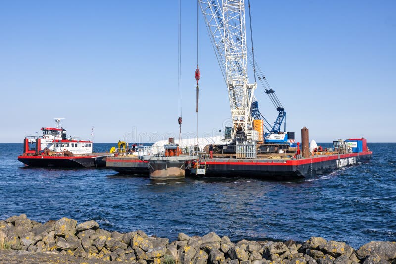 Lelystad, The Netherlands - April 22, 2022: Crane ship and supply vessel busy with demolition old offshore wind turbine. Lelystad, The Netherlands - April 22, 2022: Crane ship and supply vessel busy with demolition old offshore wind turbine