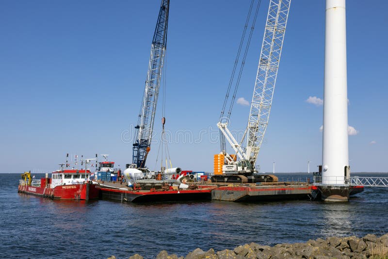 Lelystad, The Netherlands - April 22, 2022: Crane ship and supply vessel busy with demolition old offshore wind turbine. Lelystad, The Netherlands - April 22, 2022: Crane ship and supply vessel busy with demolition old offshore wind turbine