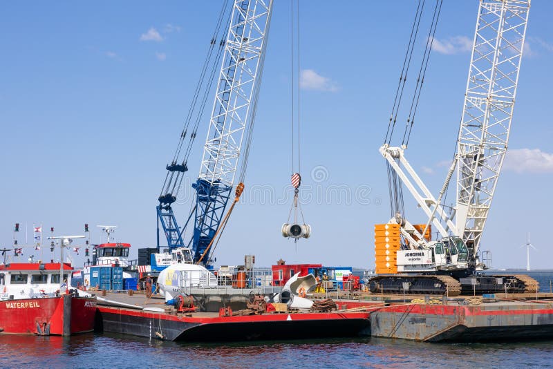 Lelystad, The Netherlands - April 22, 2022: Crane ship and supply vessel busy with demolition old offshore wind turbine. Lelystad, The Netherlands - April 22, 2022: Crane ship and supply vessel busy with demolition old offshore wind turbine