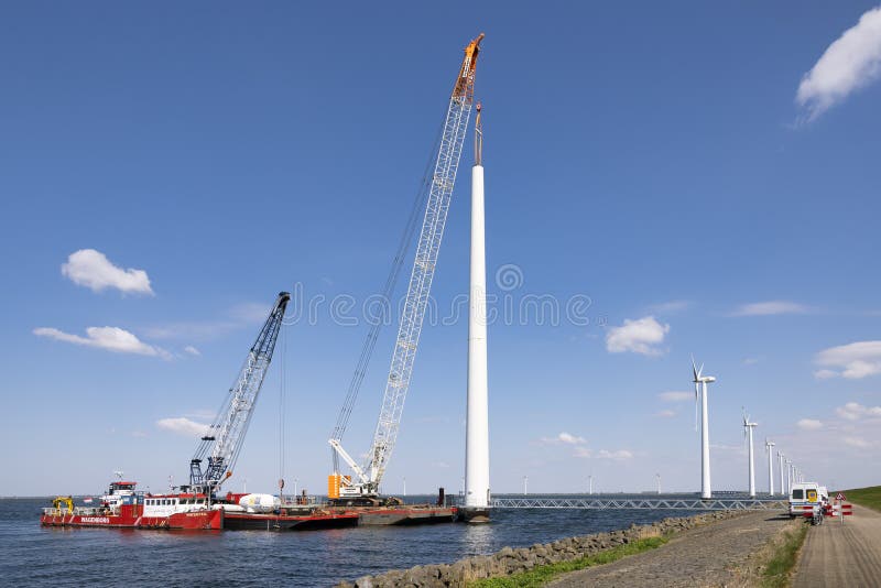 Lelystad, The Netherlands - April 22, 2022: Crane ship and supply vessel busy with demolition old offshore wind turbine. Lelystad, The Netherlands - April 22, 2022: Crane ship and supply vessel busy with demolition old offshore wind turbine