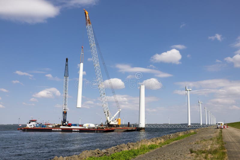 Lelystad, The Netherlands - April 22, 2022: Crane ship and supply vessel busy with demolition old offshore wind turbine. Lelystad, The Netherlands - April 22, 2022: Crane ship and supply vessel busy with demolition old offshore wind turbine