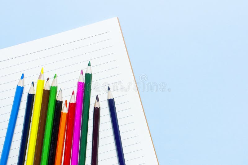 Crayons de couleur et carnet propre dans la ligne sur l'espace étendu plat bleu de copie de vue supérieure de fond Crayons coloré photographie stock libre de droits Crayons de couleur et carnet propre dans la ligne sur l'espace étendu plat bleu de copie de vue supérieure de fond Crayons coloré photographie stock libre de droits