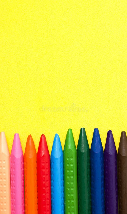 Crayons of different colors on a yellow background stock photography