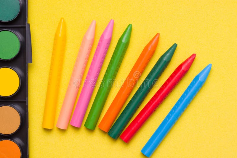 Crayons and paints on a yellow background. stock images