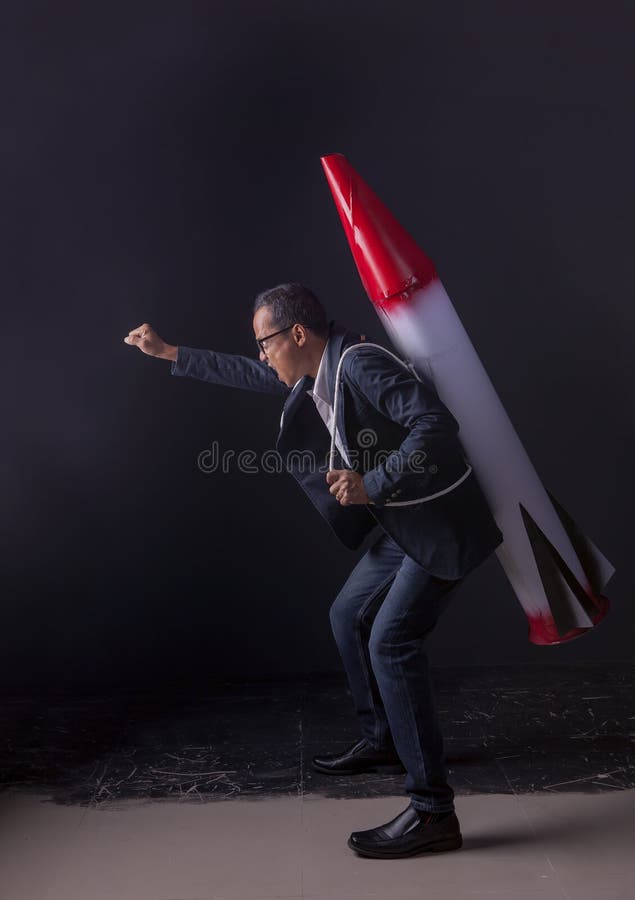 Crazy business man carrying missile weapon standing in dark stud