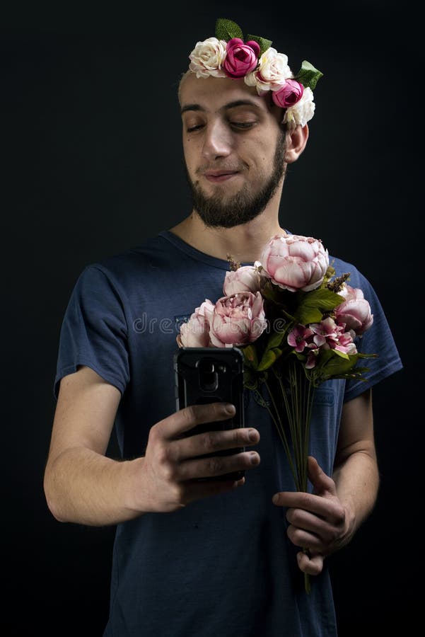Crazy funny guy talking a selfie while holding a bouquet and wearing a flower hairband stock photos Crazy funny guy talking a selfie while holding a bouquet and wearing a flower hairband stock photos