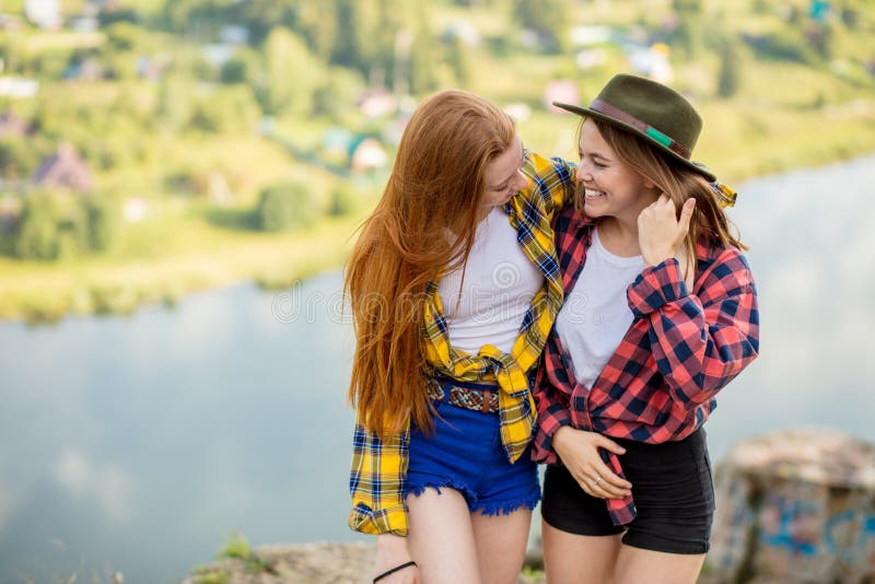 Crazy funny sisters in stylish shirts and shorts having fun on the top of rock royalty free stock image