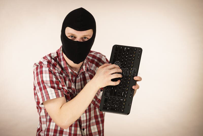 Man wearing balaclava holding keyboard royalty free stock photo