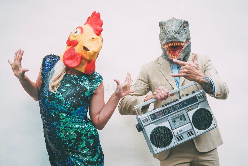 Crazy Seniorenpaar mit Hühnchen- und T-Rex-Maske beim Tanzen im Freien - Reife trendige Leute feiern Spaß