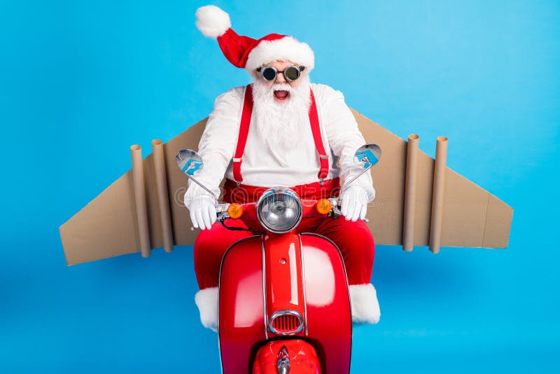 Crazy stylish modern white grey hair bearded santa claus with craft wings drive scooter hurry x-mas party wear red royalty free stock photography