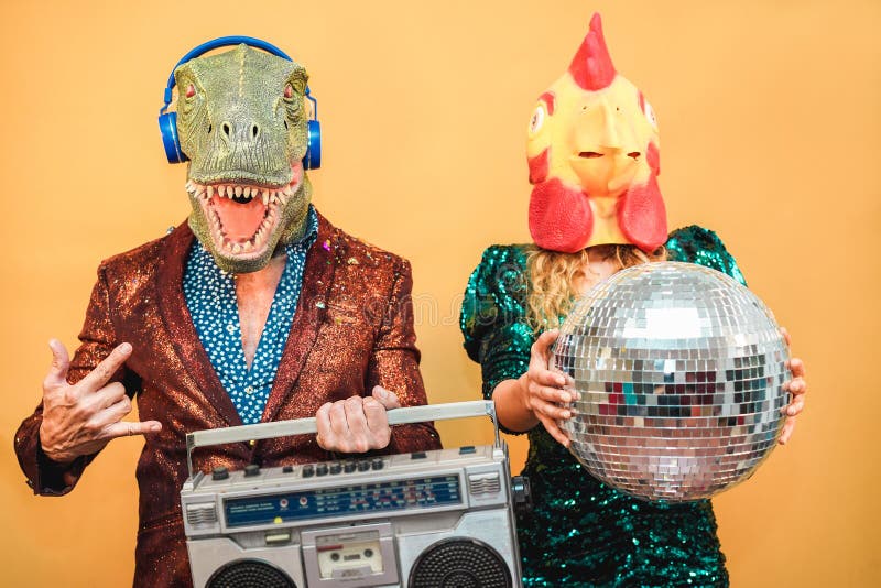 Crazy stylish people listening music with vintage boombox stereo - Fashion couple wearing t-rex and chicken mask at party fest