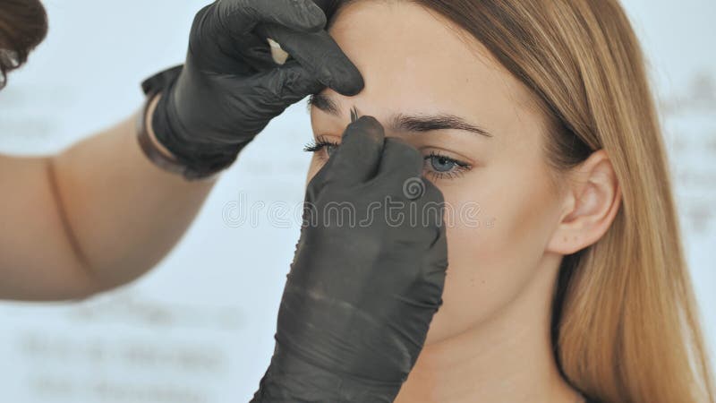 Create permanent eyebrow makeup. Peeling with tweezers. stock photo Create permanent eyebrow makeup. Peeling with tweezers. stock photo