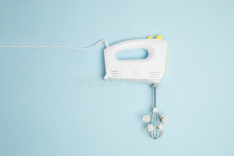 Creatief concept gemaakt van witte elektrische handmixer met boetseerapparaten en witte rozenbloemen op pastelblauwe achtergrond.