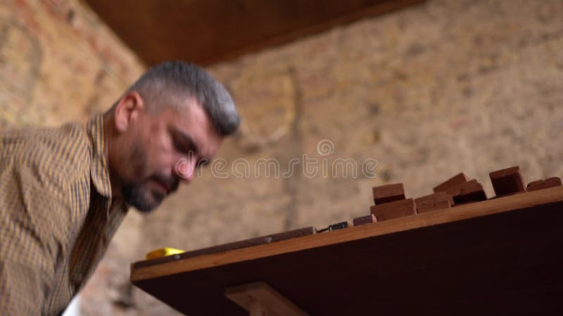 Creatieve timmerman die houten materiaal controleren verdere verwerking