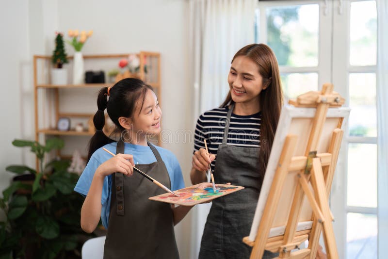 Creative bonding activity: Mother and daughter painting together in a cozy environment stock photography