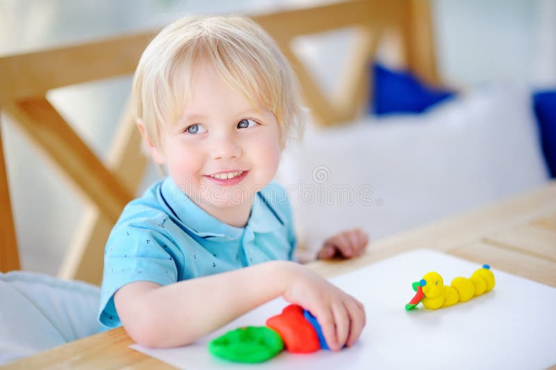 Creative boy playing with colorful modeling clay at kindergarten