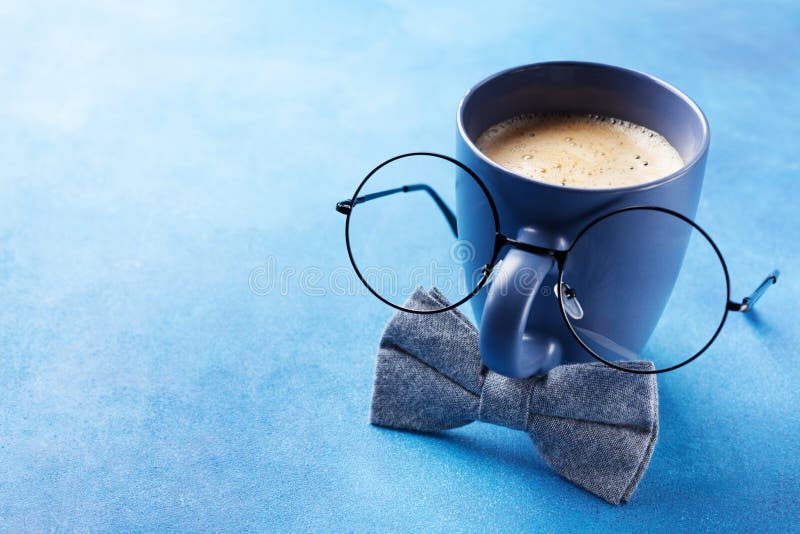 Creative breakfast on Happy Fathers Day with funny face from cup of coffee, eyeglasses and blue bowtie.