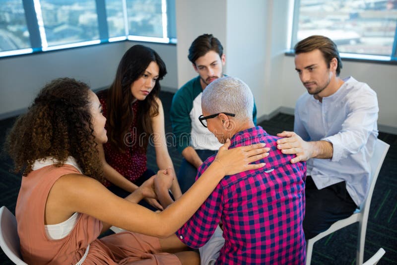 Creative business team consoling upset colleague at office