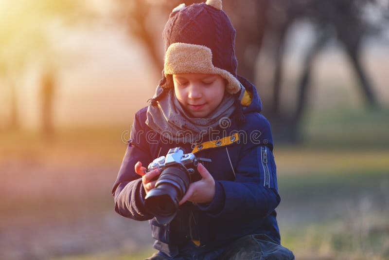 Creative child, kid photographer a little boy with a camera taking landscape pictures in warm sunset light stock photo Creative child, kid photographer a little boy with a camera taking landscape pictures in warm sunset light stock photo