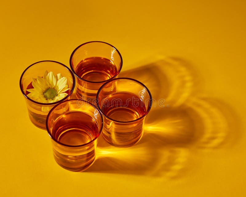 Set with yellow glasses with water and flower with shadows on a yellow paper background. Top view royalty free stock photography Set with yellow glasses with water and flower with shadows on a yellow paper background. Top view royalty free stock photography