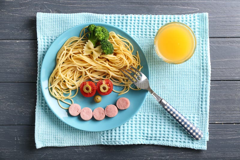 Creative composition with spaghetti and cut sausage on wooden table