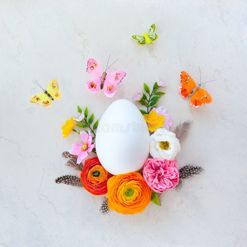 Creative Easter concept made of white egg, butterfly and spring flowers around on vintage background. Flat lay royalty free stock photography