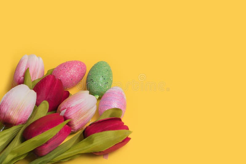 Creative Easter decotation made of colorful eggs and tulips on illuminating yellow background stock photo