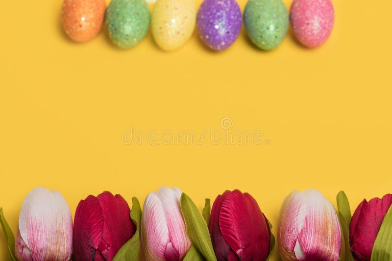 Creative Easter frame made of colorful eggs and tulips on illuminating yellow background stock photography
