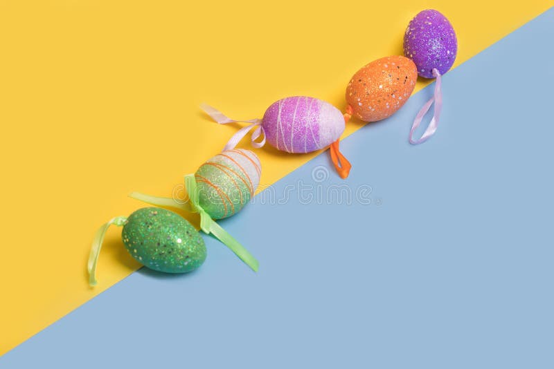 Creative Easter layout made of colorful eggs arranged diagonally on illuminating yellow and blue background royalty free stock photography