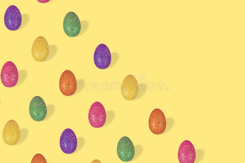 Creative Easter pattern made of colorful eggs arranged on illuminating yellow background royalty free stock image