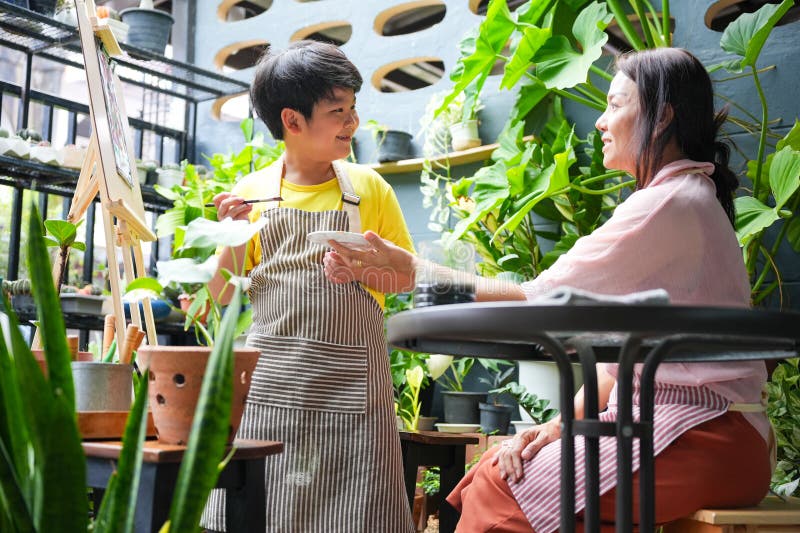 Creative Family Moment Son målning som modervaktar i en Lush Garden som sätter asiatisk mor och son som gillar hobies utomhus royaltyfria foton