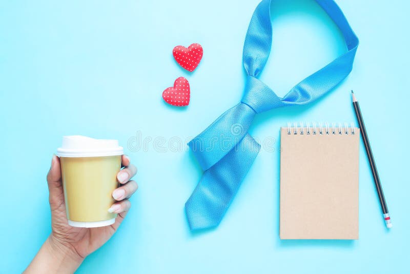 Creative flat lay of Father`s Day concept. Necktie, notebook and woman hand holding coffee cup on pastel colour royalty free stock photography Creative flat lay of Father`s Day concept. Necktie, notebook and woman hand holding coffee cup on pastel colour royalty free stock photography