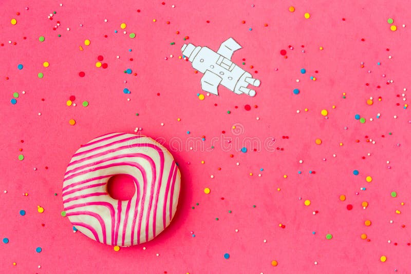 Creative Food Minimalism, Donut in Shape of Planet in Pink Sky with Space Ship Top View, Copy Space. stock photo Creative Food Minimalism, Donut in Shape of Planet in Pink Sky with Space Ship Top View, Copy Space. stock photo