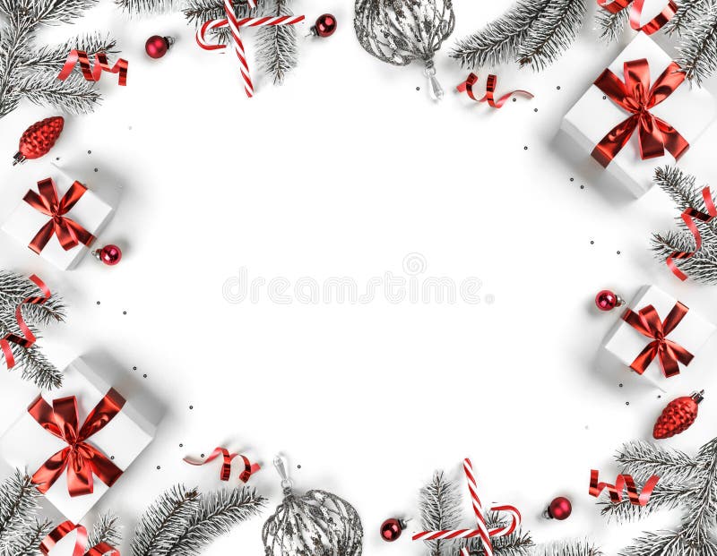 Creative frame made of Christmas fir branches, gift boxes, red decoration, sparkles and confetti on white background. Xmas