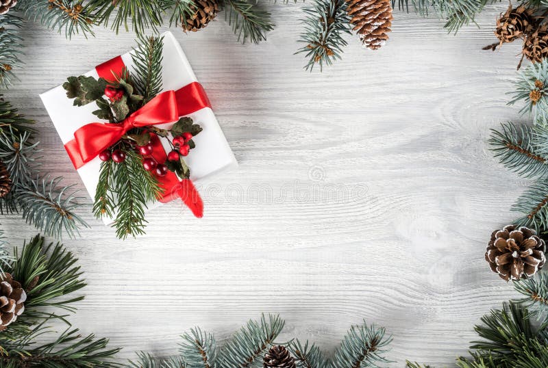 Creative frame made of Christmas fir branches on white wooden background with gift box, pine cones. Xmas and New Year theme stock photos Creative frame made of Christmas fir branches on white wooden background with gift box, pine cones. Xmas and New Year theme stock photos