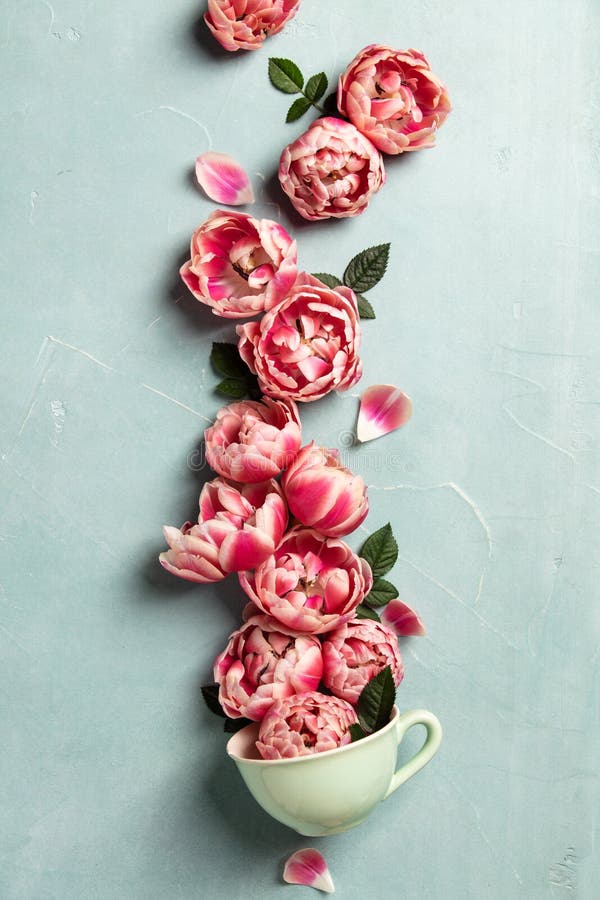 Creative layout made of coffee or tea cup with pink flowers on blue background