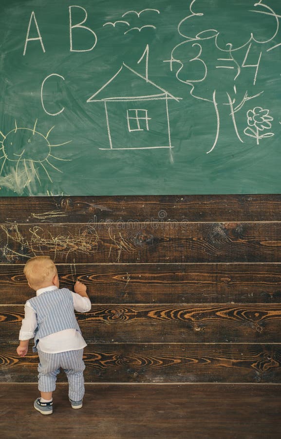 Creative little boy painting doodle on wall in classroom. Creative artist in school stock photo Creative little boy painting doodle on wall in classroom. Creative artist in school stock photo